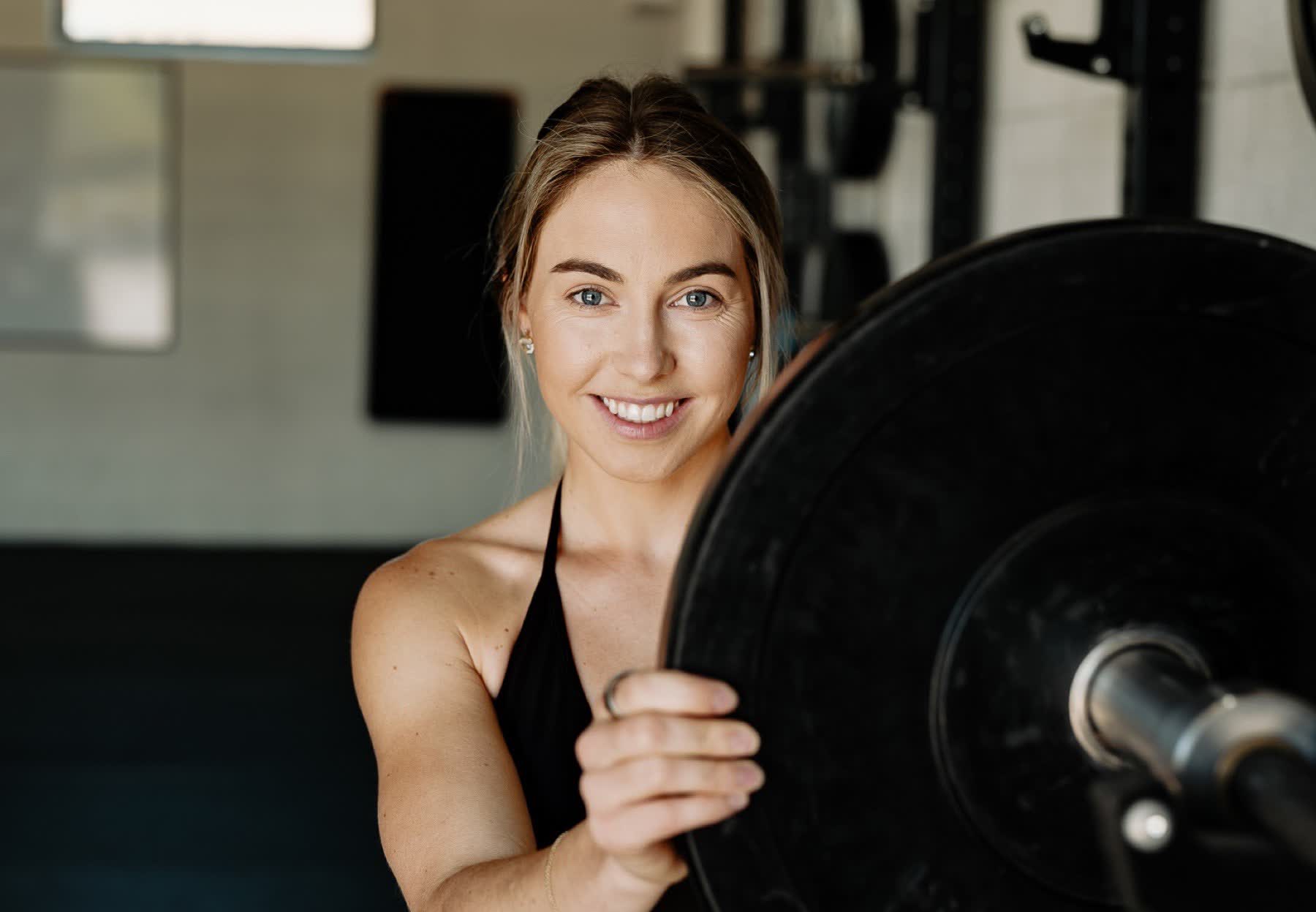 Smiling member resting behind a barbell plate