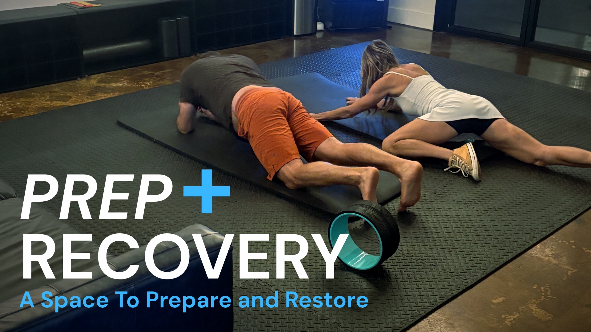 Prep + Recovery: a space to prepare and restore. Two members stretching on mats.
