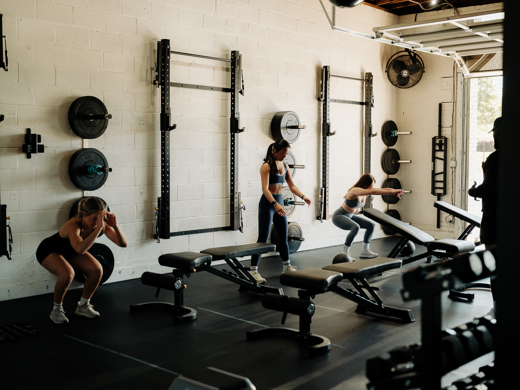 A strength class working through squats along the plate wall